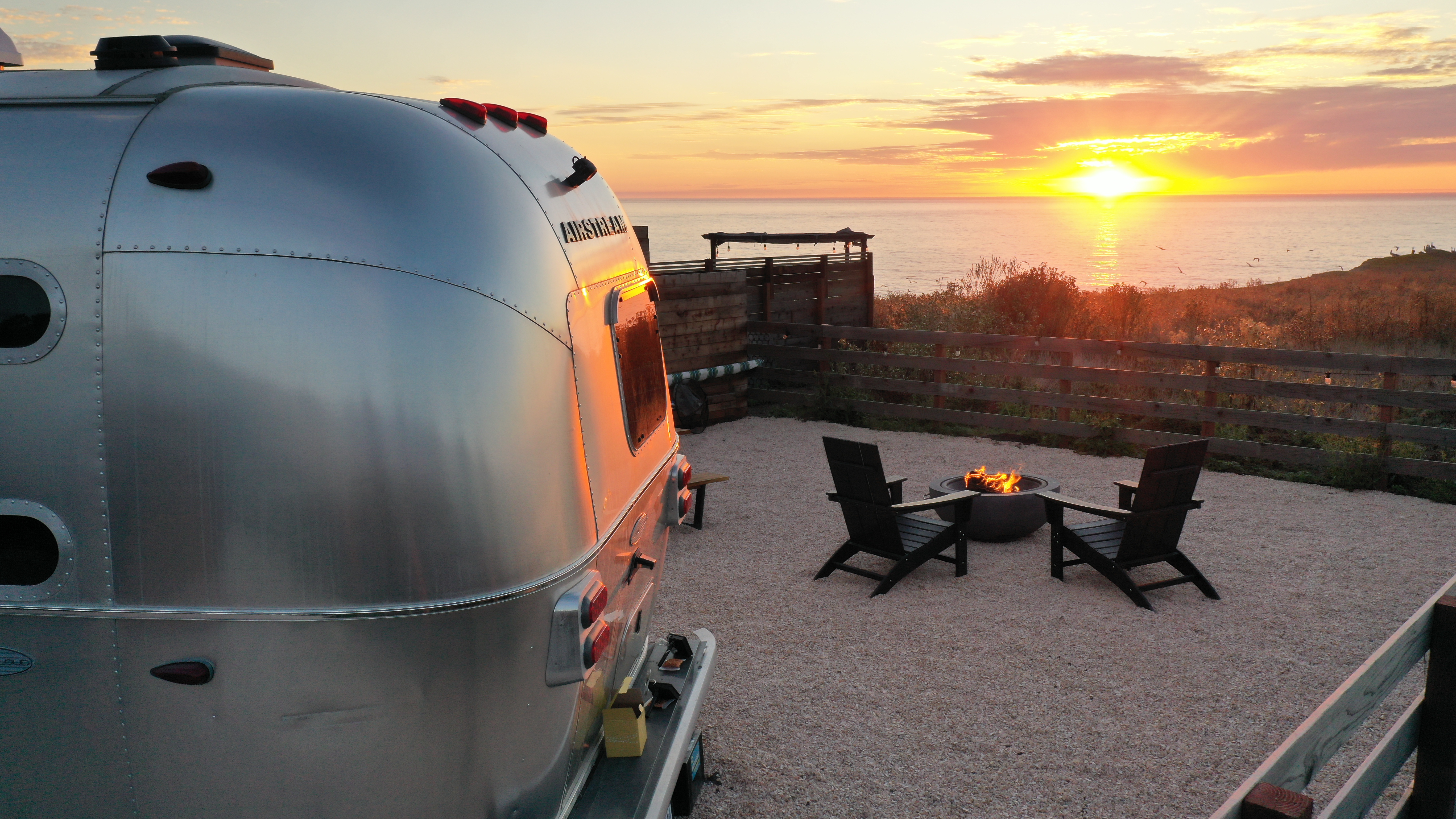 Cool California Coast Airstream glamping with fire pit at sunset on the Pacific at Airdreams